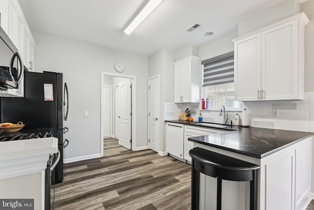 kitchen featuring sink, white cabinets, dark hardwood / wood-style flooring, backsplash, and stainless steel appliances