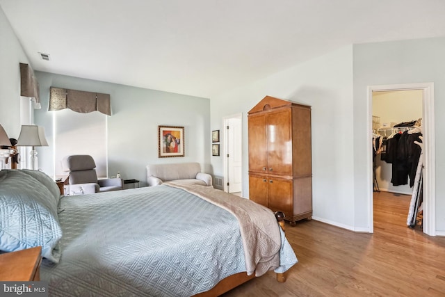 bedroom with a spacious closet, light hardwood / wood-style floors, and a closet