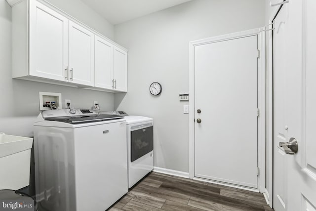 clothes washing area featuring separate washer and dryer, sink, dark hardwood / wood-style floors, and cabinets