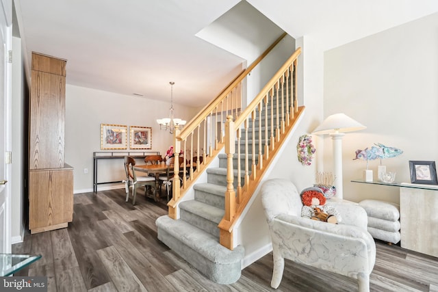 stairs with hardwood / wood-style flooring and a notable chandelier