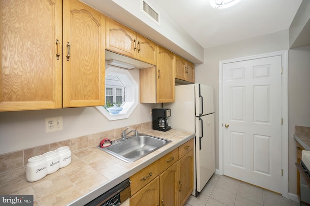 kitchen with white refrigerator, light tile patterned flooring, sink, and tile counters