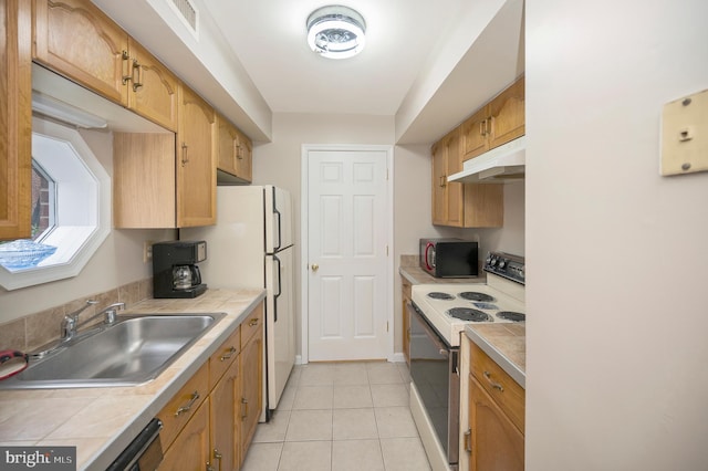 kitchen with sink, light tile patterned floors, tile counters, and white appliances