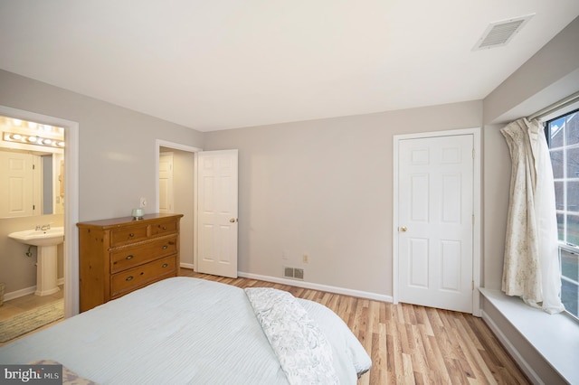 bedroom featuring ensuite bathroom and light wood-type flooring