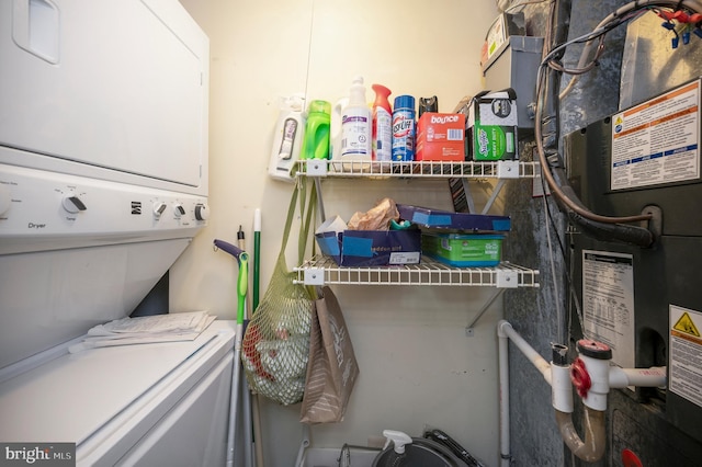 laundry room with heating unit and stacked washer and dryer