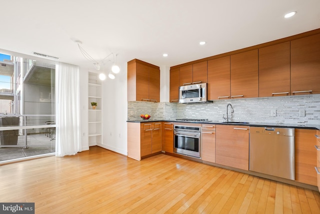 kitchen with sink, backsplash, stainless steel appliances, and light hardwood / wood-style floors