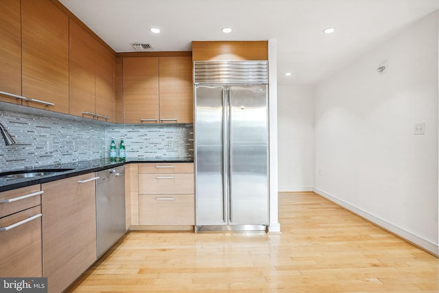 kitchen with sink, decorative backsplash, light hardwood / wood-style floors, and appliances with stainless steel finishes