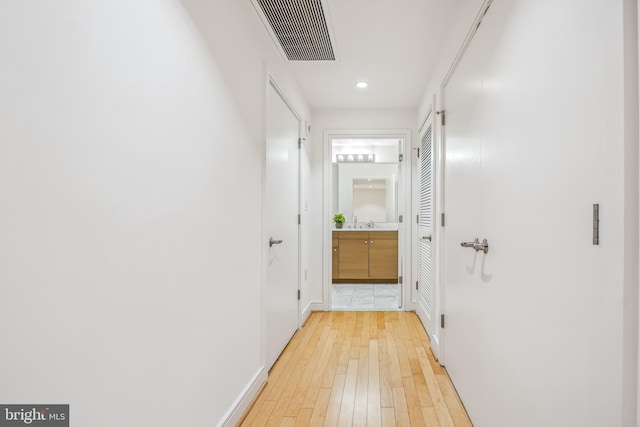 corridor featuring sink and light hardwood / wood-style floors