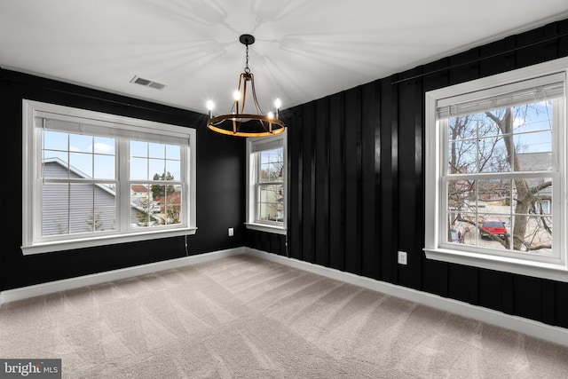 carpeted empty room featuring a chandelier