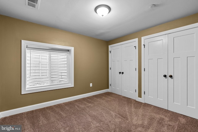 unfurnished bedroom featuring two closets and carpet