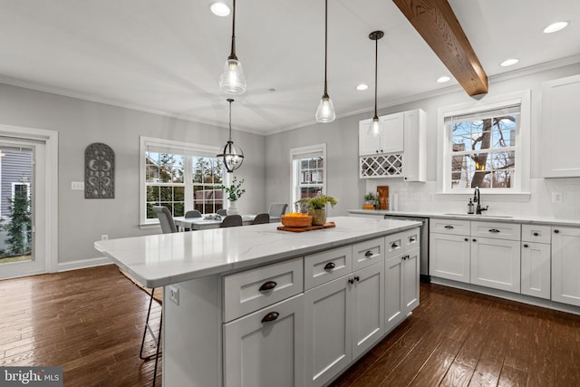 kitchen featuring sink, white cabinetry, a kitchen island, pendant lighting, and light stone countertops