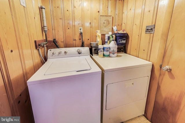 laundry area featuring wooden walls and washing machine and dryer