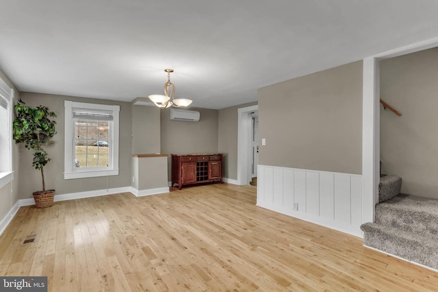 unfurnished living room with light hardwood / wood-style floors and an AC wall unit