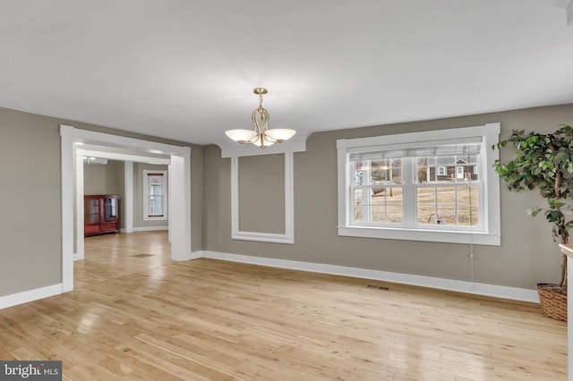 unfurnished dining area with a chandelier and light hardwood / wood-style flooring