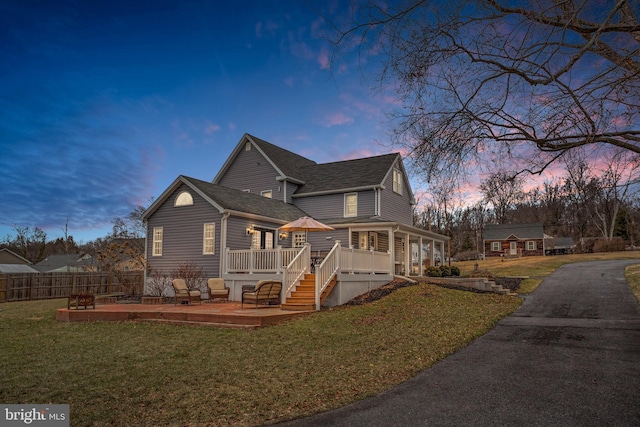 property exterior at dusk featuring a wooden deck and a yard