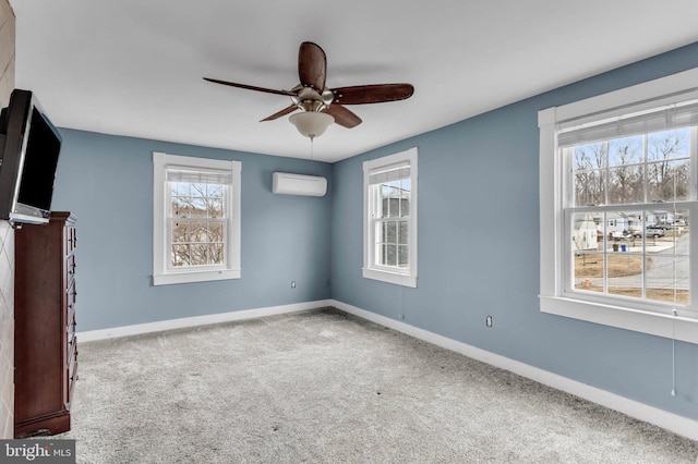 carpeted spare room featuring ceiling fan, an AC wall unit, and a healthy amount of sunlight