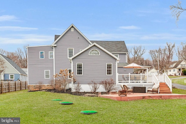 rear view of house with a wooden deck, a lawn, and a patio area