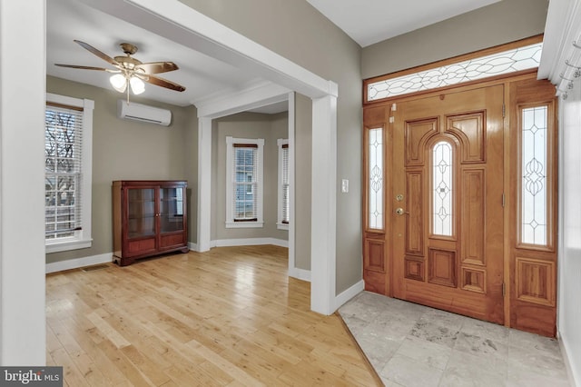 foyer entrance featuring light hardwood / wood-style flooring, a wall unit AC, and ceiling fan