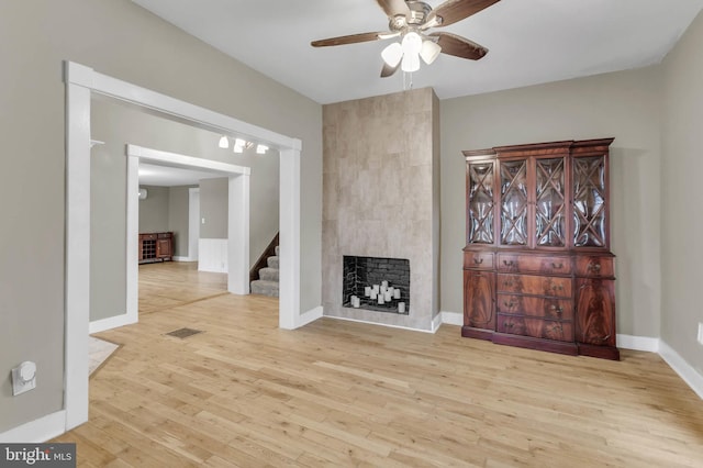 living room featuring ceiling fan, light wood-type flooring, and a fireplace