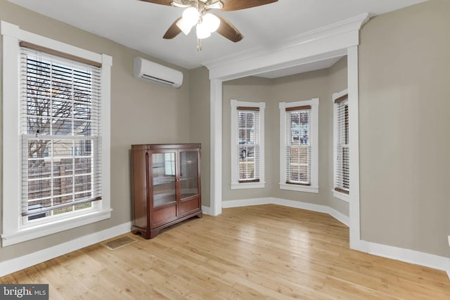 unfurnished room featuring ceiling fan, a wall mounted AC, and light wood-type flooring