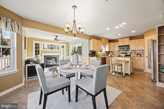 dining space featuring recessed lighting, baseboards, a glass covered fireplace, and ceiling fan with notable chandelier