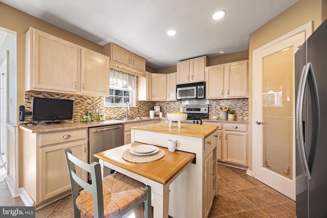 kitchen featuring backsplash, light brown cabinetry, recessed lighting, stainless steel appliances, and a sink