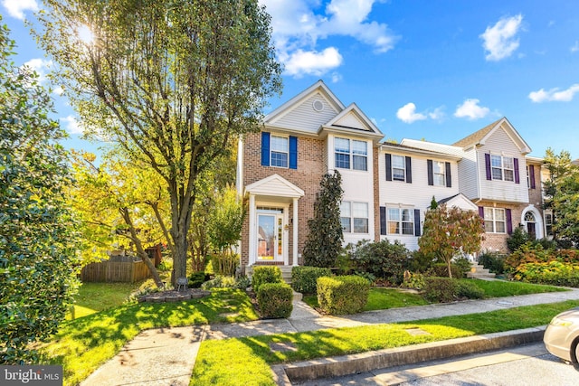 view of front of house featuring a front lawn, fence, and brick siding