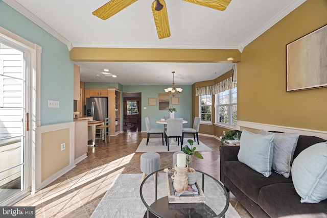 living area with ceiling fan with notable chandelier, baseboards, and ornamental molding