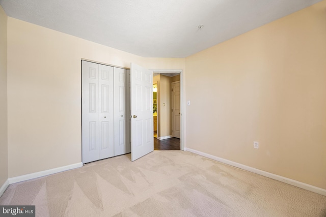 unfurnished bedroom featuring baseboards, carpet floors, and a closet