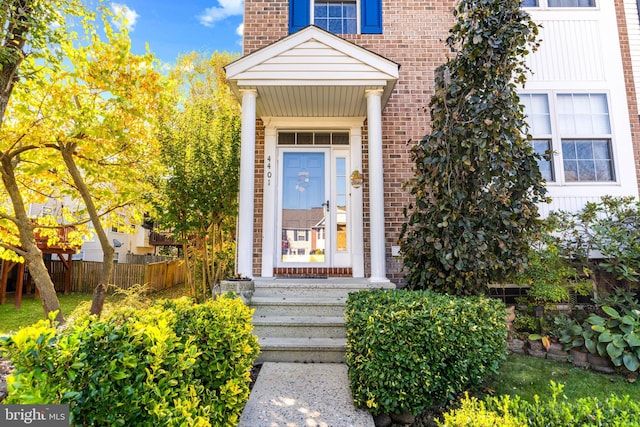 entrance to property with brick siding and fence