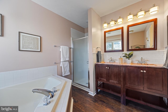 full bath with double vanity, a stall shower, a garden tub, and a sink