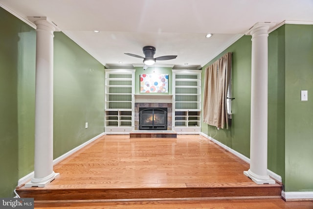 unfurnished living room featuring a tiled fireplace, a ceiling fan, ornate columns, and ornamental molding