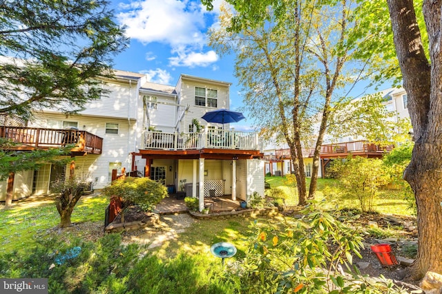 rear view of house featuring a yard, a patio, and a deck