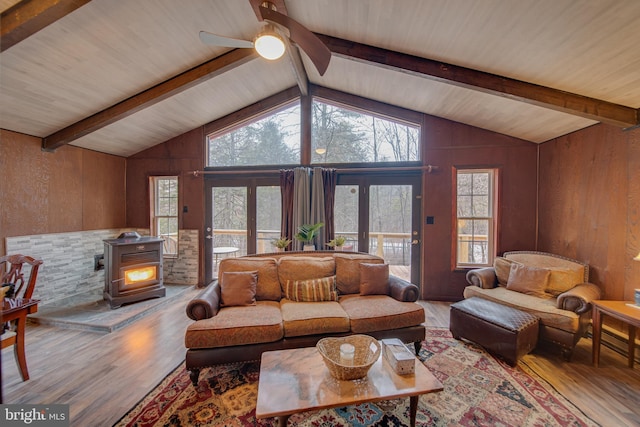 living room featuring a wood stove, hardwood / wood-style floors, vaulted ceiling with beams, and wood walls