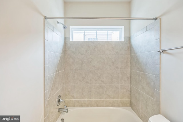 bathroom featuring tiled shower / bath combo and toilet