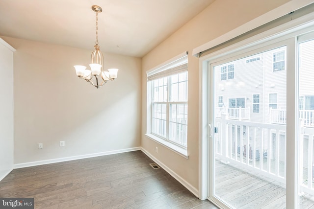 unfurnished dining area featuring a notable chandelier and dark hardwood / wood-style floors