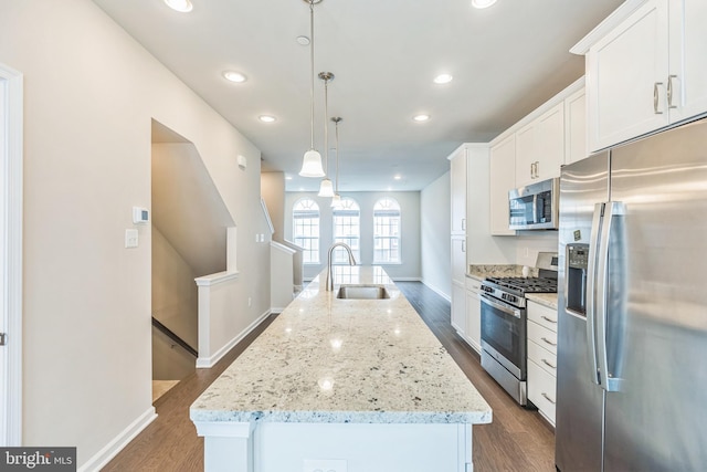 kitchen with a kitchen island with sink, hanging light fixtures, white cabinets, and appliances with stainless steel finishes