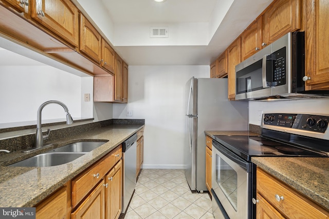 kitchen featuring light tile patterned flooring, stainless steel appliances, sink, and dark stone counters