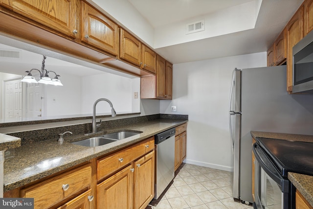 kitchen featuring sink, light tile patterned floors, appliances with stainless steel finishes, dark stone countertops, and hanging light fixtures