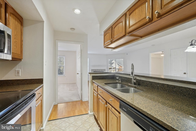 kitchen featuring stainless steel appliances, a wealth of natural light, sink, and dark stone countertops