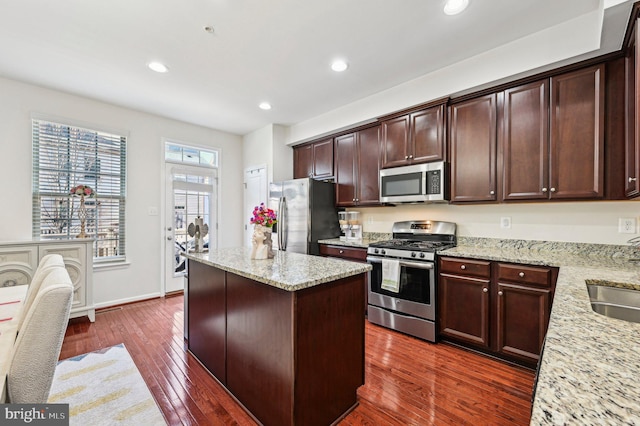 kitchen featuring light stone counters, stainless steel appliances, dark hardwood / wood-style floors, and a kitchen island