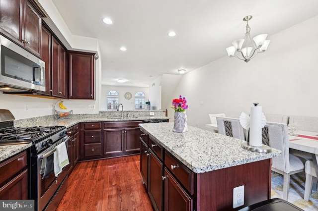 kitchen featuring sink, appliances with stainless steel finishes, dark hardwood / wood-style floors, a center island, and decorative light fixtures