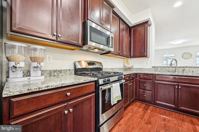 kitchen featuring sink, dark wood-type flooring, light stone countertops, and appliances with stainless steel finishes