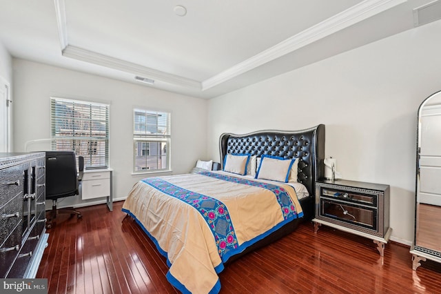 bedroom featuring a raised ceiling, ornamental molding, and dark wood-type flooring