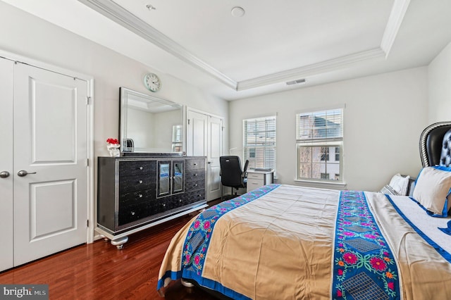 bedroom featuring crown molding, a tray ceiling, and dark wood-type flooring