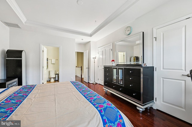 bedroom with a raised ceiling, crown molding, connected bathroom, and dark hardwood / wood-style flooring