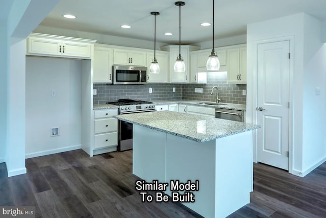 kitchen with sink, light stone counters, appliances with stainless steel finishes, a kitchen island, and white cabinets