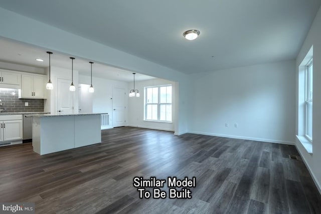 kitchen with dark wood-type flooring, white cabinetry, a center island, hanging light fixtures, and backsplash