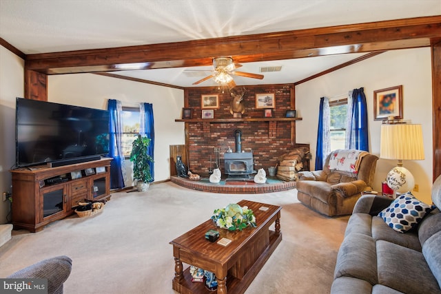 carpeted living room with beamed ceiling, ornamental molding, a wood stove, and ceiling fan