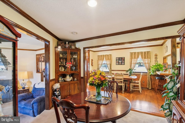 dining room featuring crown molding, a textured ceiling, and light wood-type flooring