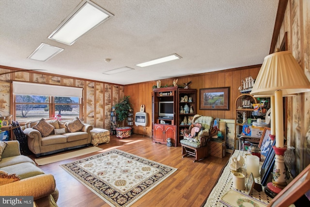 living room featuring wood-type flooring, a textured ceiling, and crown molding